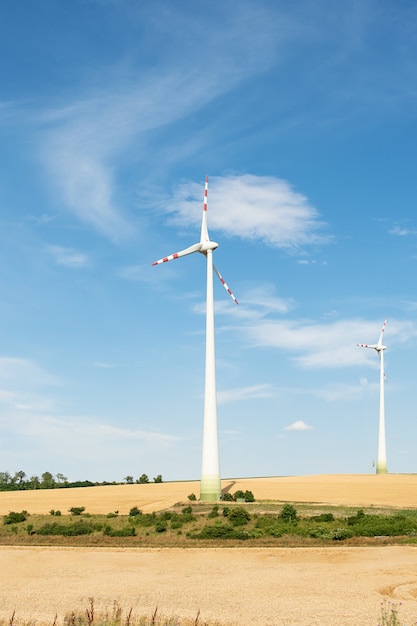 Mening van een windenergieinstallatie op een achtergrond van blauwe hemel en gebieden met korrelgewassen.