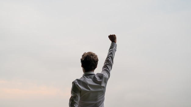 Mening van erachter van een succesvolle jonge zakenman die zich onder de hemel bevindt