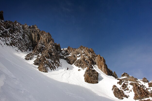 Mening van mannelijke snowboarder die in helm onderaan de berghelling loopt