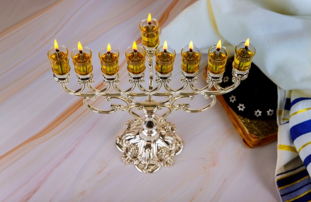 Menorah Hanukkah candles are burning in hanukkiah on light holiday day.