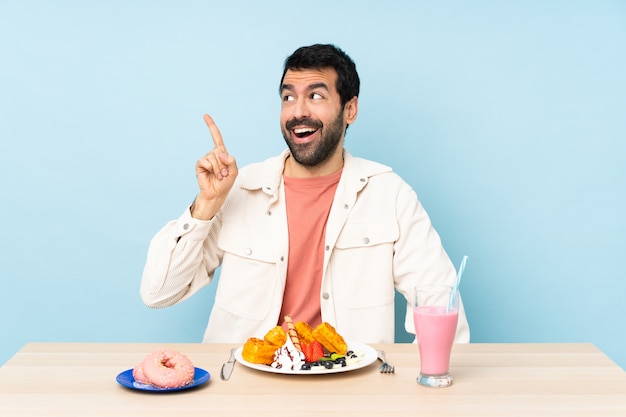 Mens aan een tafel met ontbijtwafels en een milkshake die de oplossing wil realiseren terwijl hij een vinger opheft