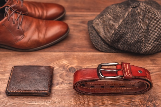 Mens accessories brown leather shoes wallet wool cap and leather belt on a wooden background