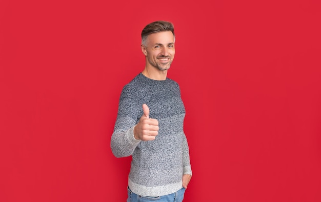 Mens beauty hair and skin care positive grizzled guy in sweater on red background hoary man portrait male fashion model winter fashion