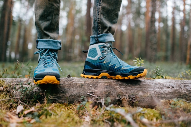 Mens benen in wandelschoenen voor outdoor activiteit staande op omgevallen boom.