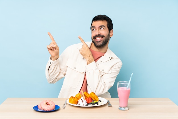 Mens bij een lijst die ontbijtwafels heeft en een milkshake die met de wijsvinger richt