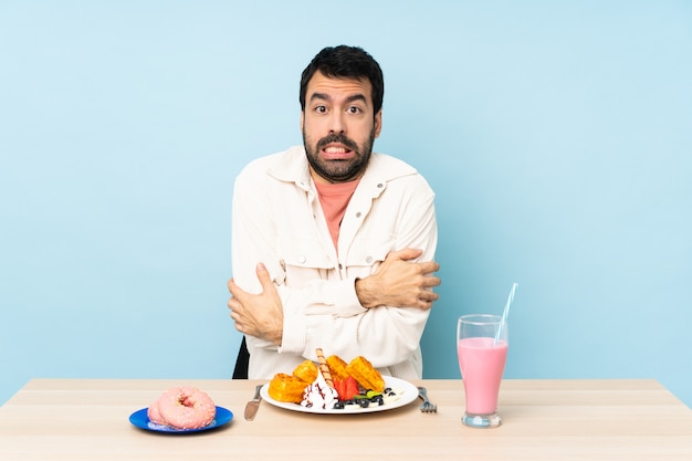 Mens bij een lijst die ontbijtwafels heeft en een milkshake het bevriezen