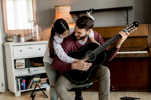 Mens die akoestische gitaar voor dochter in woonkamer thuis speelt