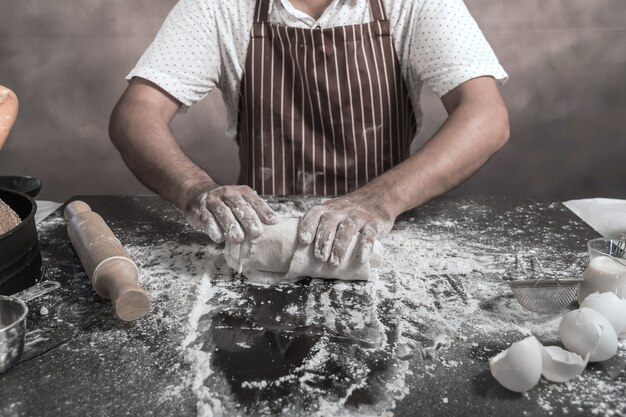 Mens die broodjes voorbereiden bij lijst in bakkerij