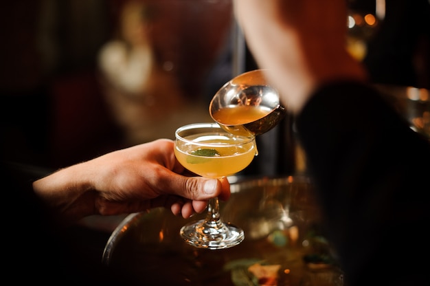 Mens die de oranje limonadedrank giet in het glas