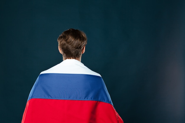 Mens die de vlag van Rusland op zwarte muur houdt