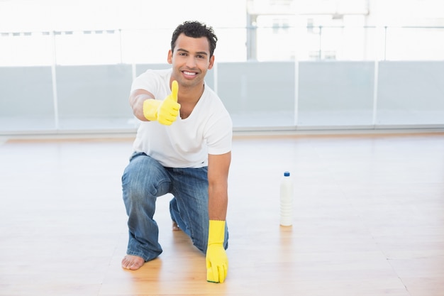 Mens die de vloer schoonmaken terwijl het gesturing omhoog beduimelt omhoog bij huis