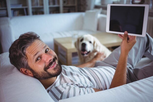 Mens die digitale tablet in woonkamer houdt