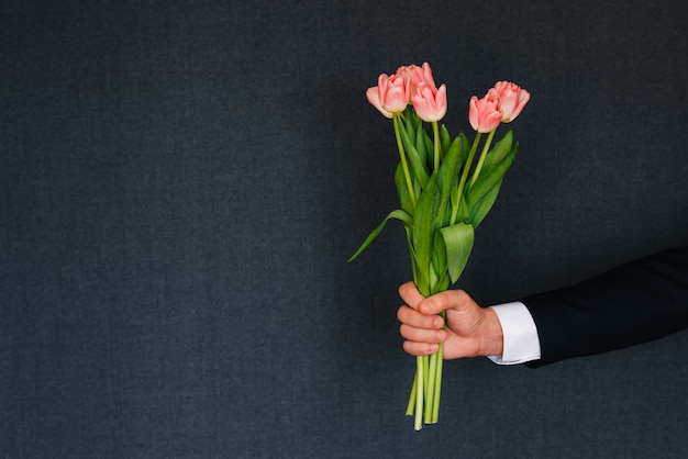 Mens die een boeket van roze tulpen geeft