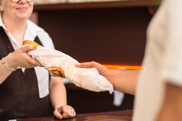 Mens die een brood van brood in een bakkerij koopt