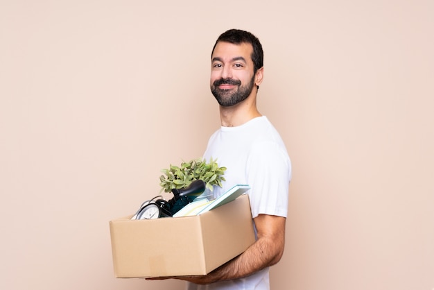 Mens die een doos houdt en zich in nieuw huis met gekruiste en wapens beweegt die vooruit kijken