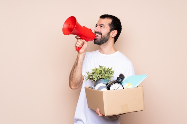 Mens die een doos houdt en zich in nieuw huis over het geïsoleerde schreeuwen door een megafoon beweegt