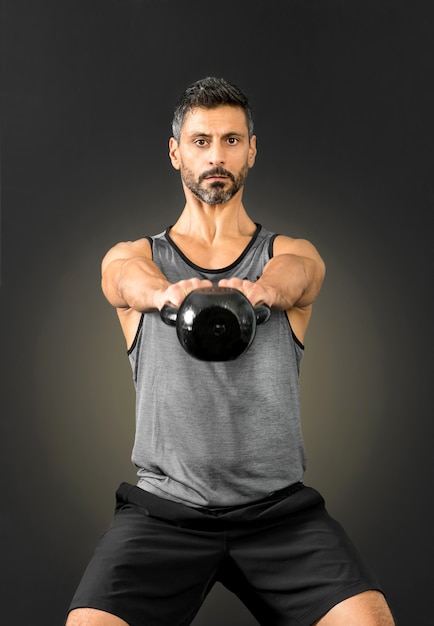 Mens die een kettlebellgewicht opheft en uitbreidt