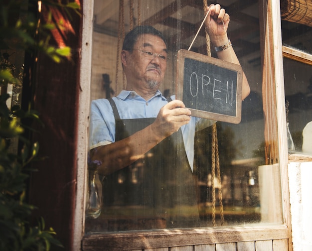 Mens die een open teken in een bloemwinkel hangt