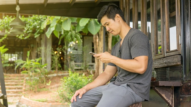 Mens die een smartphone in een tuin gebruikt