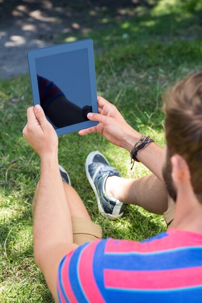 Mens die een tablet in het park gebruikt