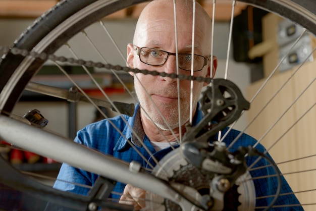 Mens die fietstoestel in zijn workshop herstelt.