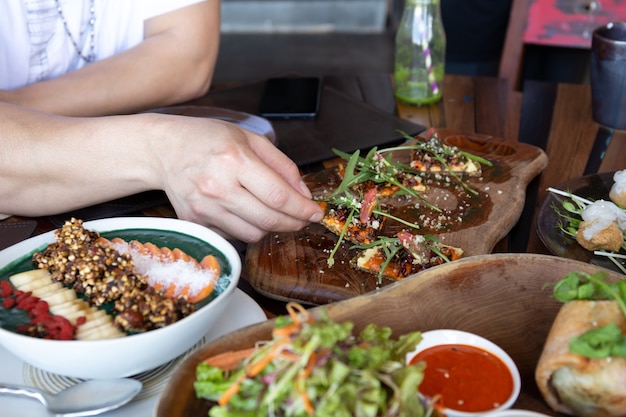 Mens die gehele korrelpizza met groenten en gezond voedsel op houten raad eet.