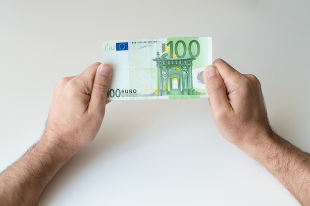 Foto mens die honderd euro bankbiljet in zijn handen houdt