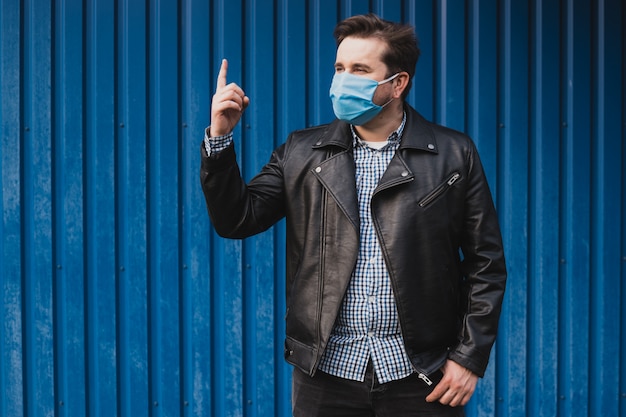 Mens die iets met zijn vinger toont en masker, coronavirus quarantaine draagt.