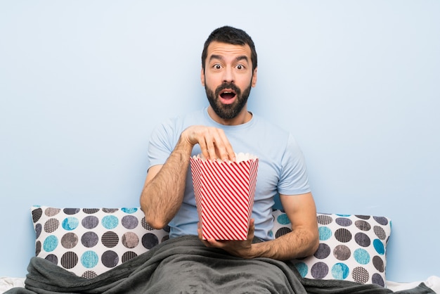 Mens die in bed met baard popcorns eet