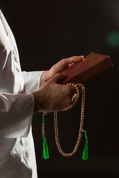 Mens die in traditionele Arabische kleren koran en gebedparels houdt