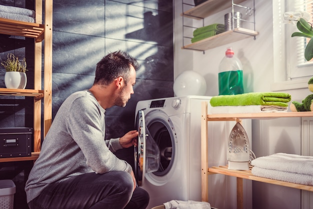 Mens die kleren zet in wasmachine