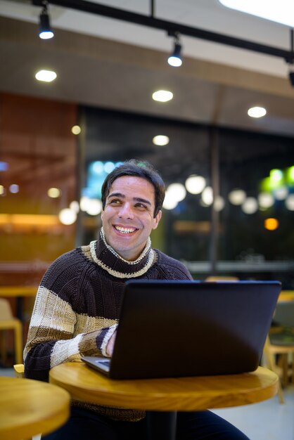 Mens die laptop computer met behulp van bij koffiewinkel