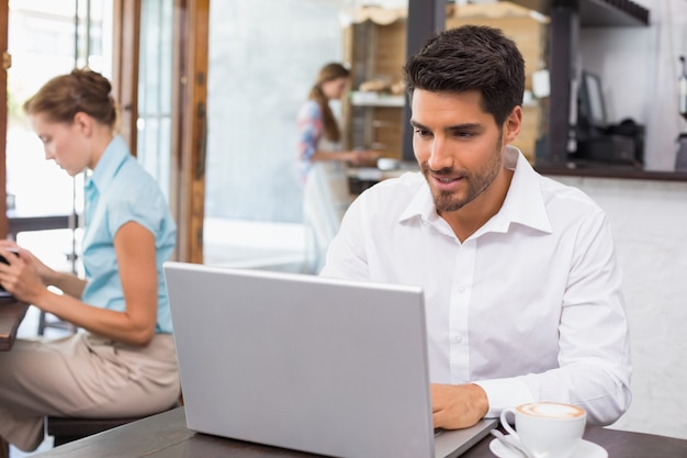 Mens die laptop in koffiewinkel met behulp van