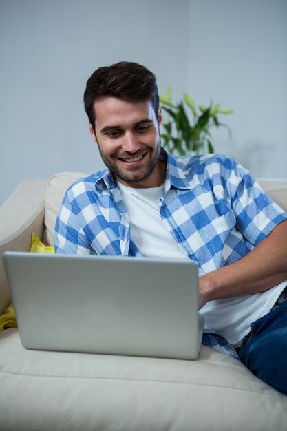 Mens die laptop met behulp van terwijl het ontspannen op bank