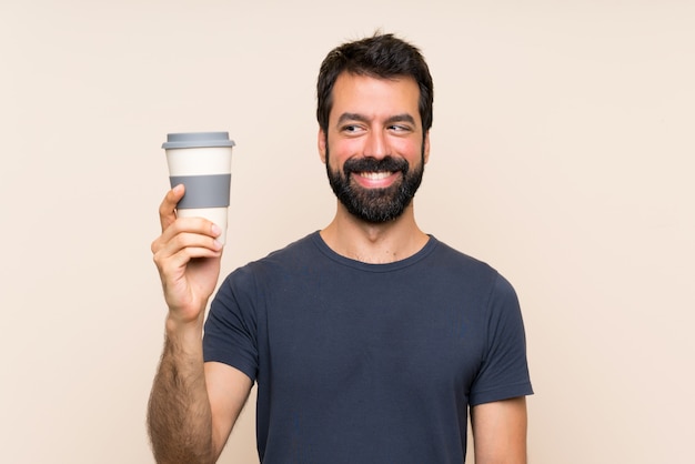 Mens die met baard een koffie met gelukkige uitdrukking houdt