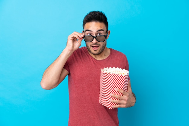 Mens die met baard popcorns over geïsoleerde muur houden