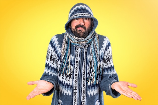 Foto mens die met de winterkleren onbelangrijk gebaar op kleurrijke achtergrond maken
