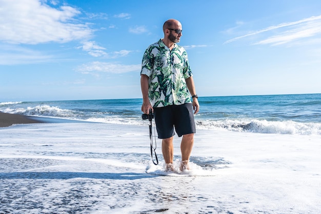 Mens die met een camera langs het strand loopt