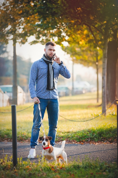 Mens die met hond bij de steeg van het de herfstseizoen loopt.