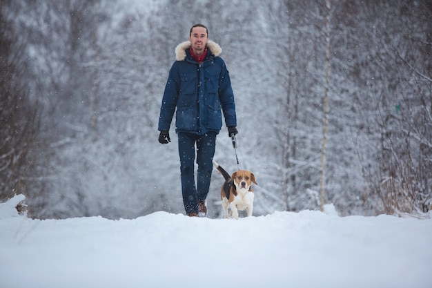 Mens die met hondbrak in de winter lopen. Sneeuwende dag