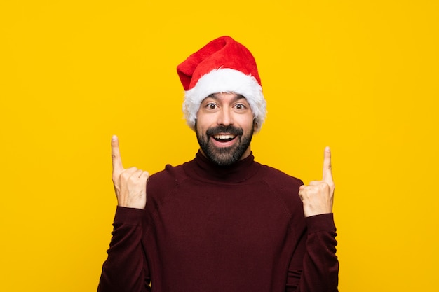 Mens die met Kerstmishoed over geïsoleerde gele muur een groot idee benadrukt