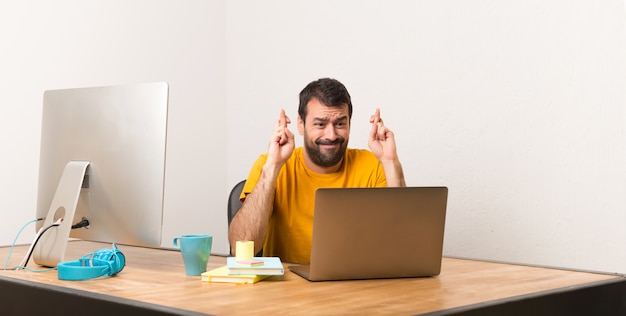 Mens die met laptot in een bureau met vingers werken die en het beste kruisen wensen