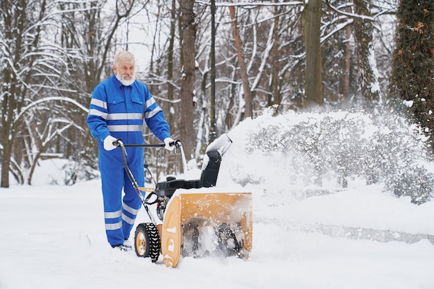 Mens die met sneeuwblazer werkt en sneeuw verwijdert uit voetpad