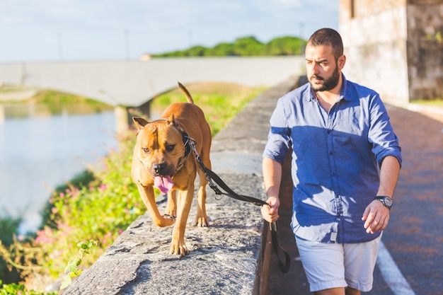 Foto mens die met zijn hond loopt.