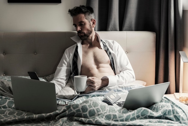 Mens die mobiele telefoon met behulp van terwijl het zitten op bed
