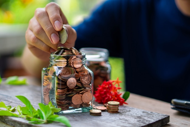 Mens die muntstukken aanbrengt aan glazen fles voor geld