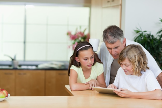 Mens die tablet bekijkt die zijn kinderen gebruiken