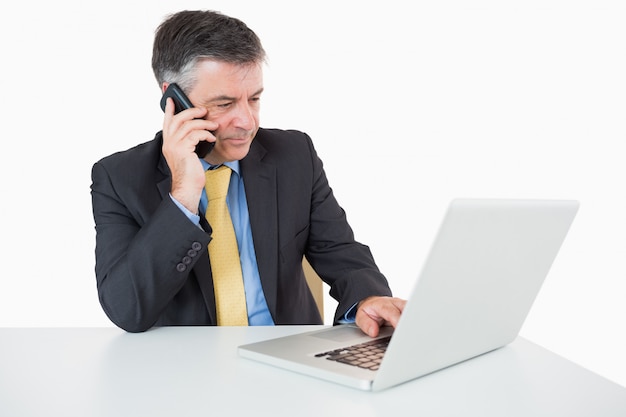 Mens die terwijl het schrijven op laptop telefoneert