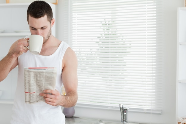 Mens die thee drinkt terwijl het lezen van het nieuws