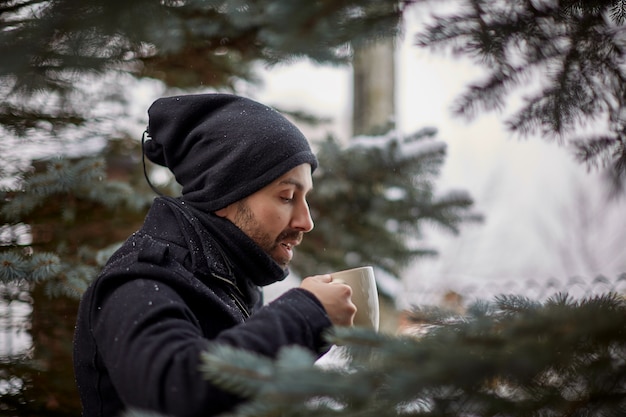 Mens die van hete koffie op sneeuwterras geniet